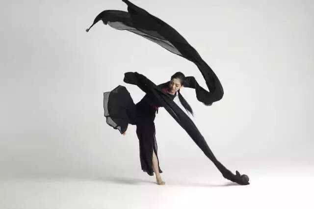Dancer in black with water sleeves striking a pose.